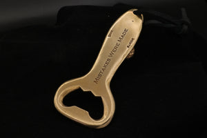 Back view of the bronze Snake Dagger Bottle Opener in bronze with leather thong cord. This side features the phrase "Mistakes Were Made' engraved.