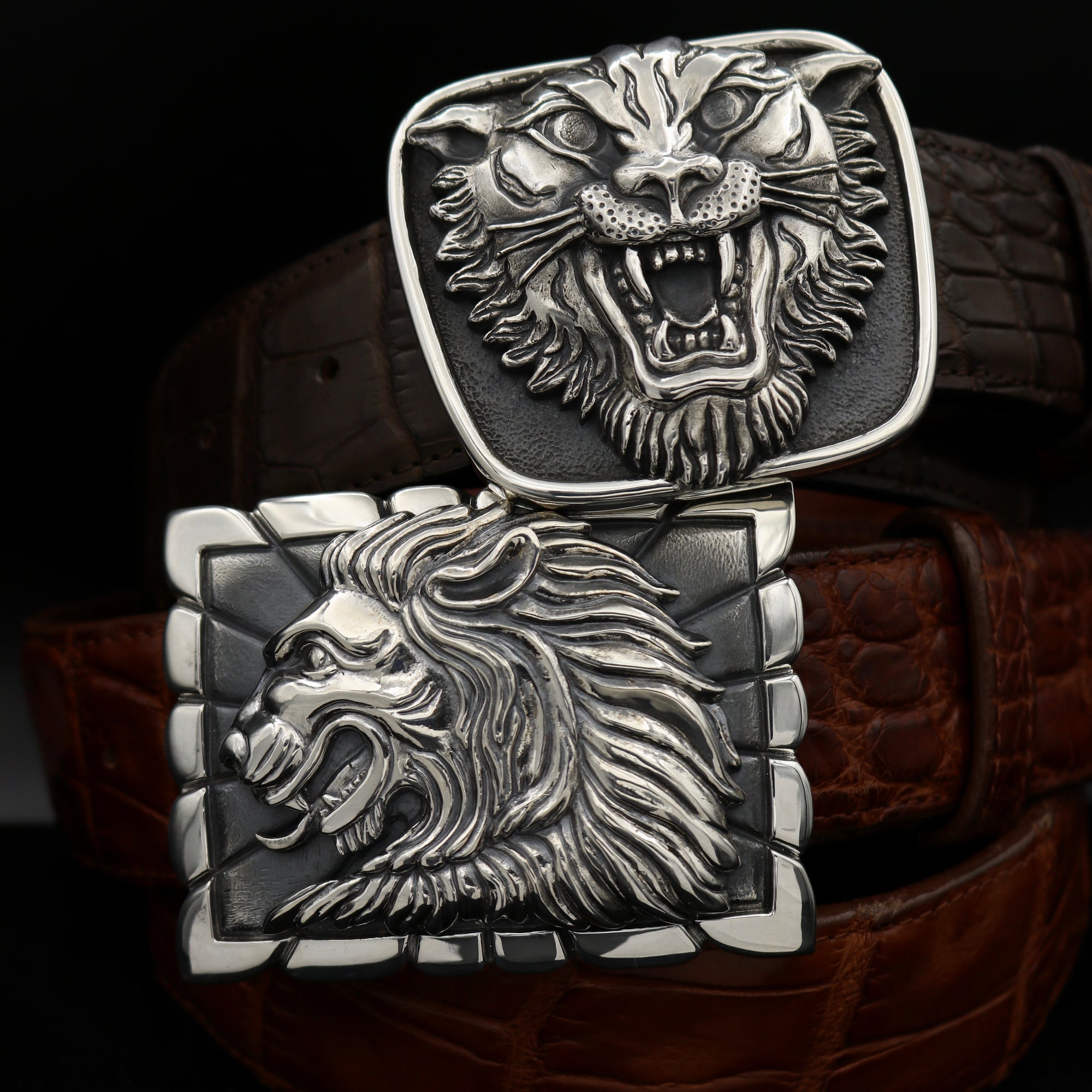 Two Trophy Buckles of Sterling Silver for men or women. Top, The Medium Tiger Head buckle and below the Lion Head in Profile buckle.