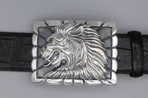 Sterling belt buckle on belt strap. Heraldic style Lion's head in profile. Sculpted in high relief atop a rectangular trophy buckle base that is textured with polished edging.
