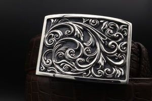 The Carved Scroll Plaque style Sterling buckle is shown in a moodily lit image.