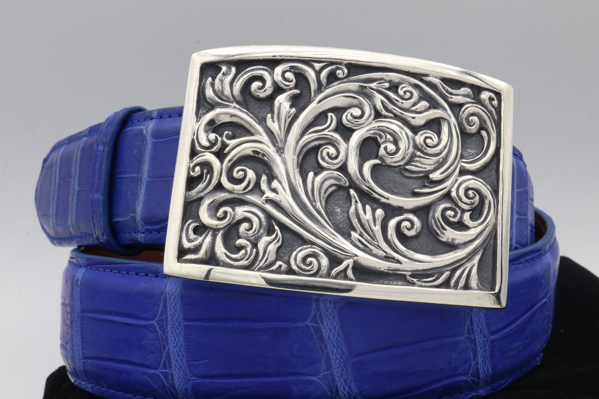 The Carved Scroll buckle,in sterling, is shown, front view on a black alligator belt.
