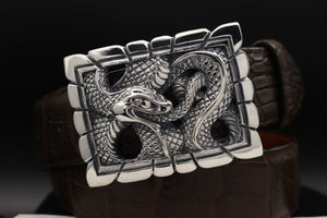 This image shows the Sterling Ouroboros Snake trophy buckle in a dramatic front on shot. It is on a coiled dark brown alligator belt.