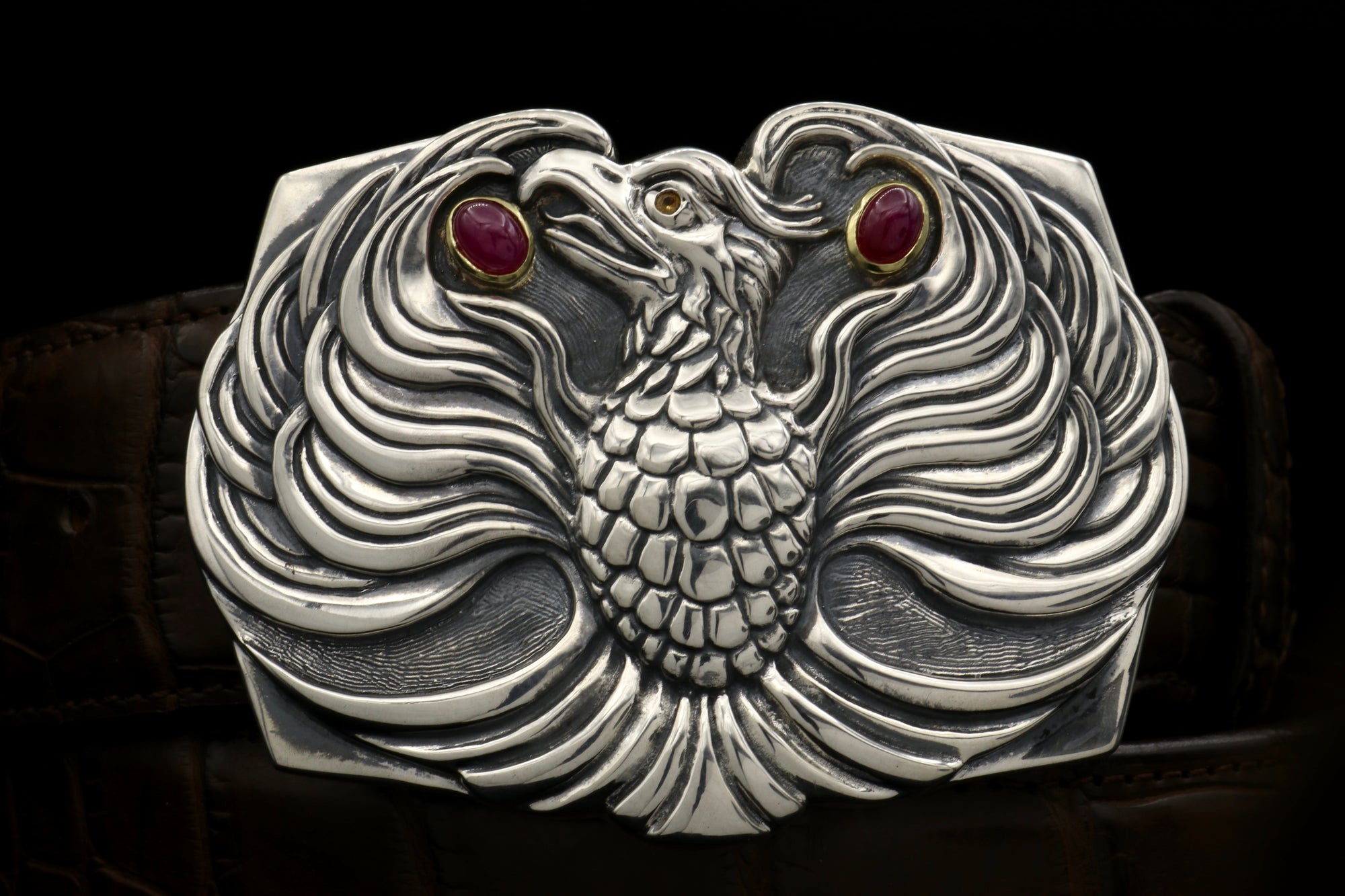 The Phoenix sterling buckle accented with 18kt gold bezel set ruby cabs and a dark yellow spessaratine eye.