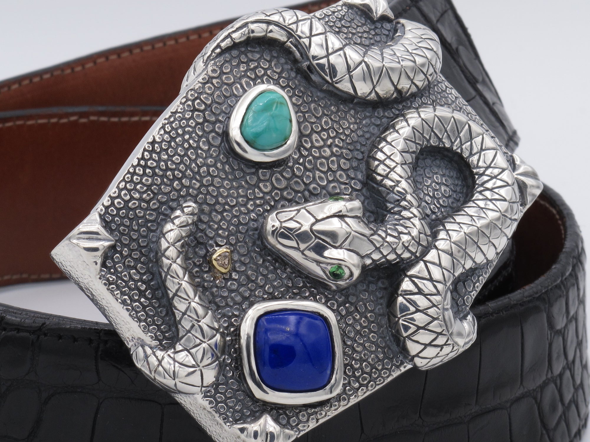 image of the Angular shaped trophy depicting a Snke drapped on it. This custom version is made with tsavorite eyes and  bezel set Lapis,Turqoise cabochons and Rough Brown Diamond [set in 18kt bezel]
