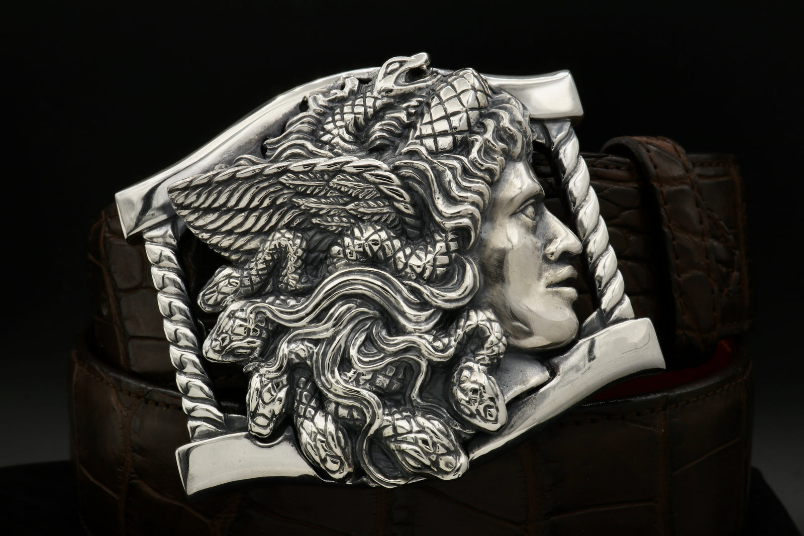 Sterling buckle Medusa head, carved as a side view. It sits on a base frame accented with twist detail.
