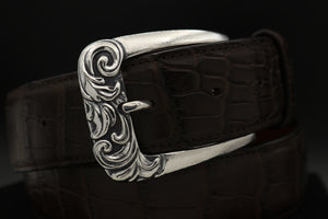 Classic Sterling harness style buckle with deep carved scroll design on front.  Shown on coiled brown alligator belt.