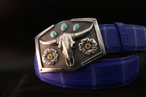 Sterling buckle with oval turquoise stones, steer skull and sterling and gold flower with rubies on a blue belt.