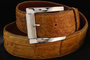 Tan  Alligator skin belt with silver buckle on a black background