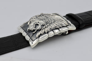 Sterling belt buckle on belt strap. Heraldic style Lion's head in profile. Sculpted in high relief atop a rectangular trophy buckle base that is textured with polished edging.  
